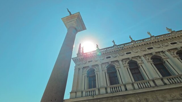 Piazzetta San Marco Column And Renaissance Building Facade With Statues Against Bright Sun And Clear Blue Summer Sky