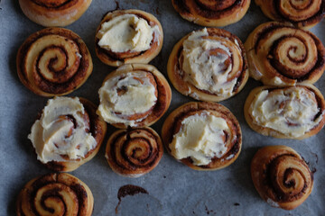 Freshly baked cinnamon rolls on a baking sheet with paper	
