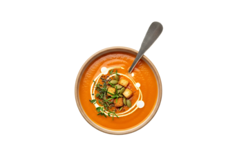 A bowl of vibrant orange pumpkin soup, garnished with croutons, pumpkin seeds, and fresh herbs, sits on a black background, showcasing a rich autumnal color palette.