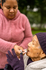 Nurse assisting elderly woman eating chocolate in park