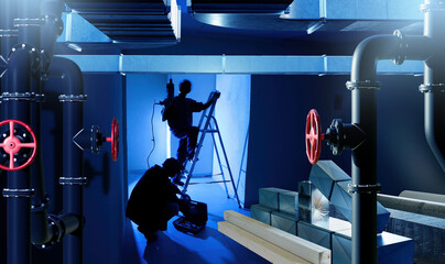 Workers installing ventilation and pipeline system in industrial building basement with tools and ladder, symbolizing construction, engineering, maintenance, plumbing.