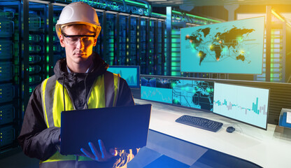 Engineer in safety vest and helmet using laptop in data center with monitoring screens, representing cybersecurity, networking, IT infrastructure, cloud computing.