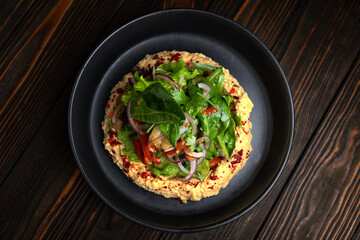 Hummus with Roasted Vegetable Salad and Fresh Greens on Dark Wooden Background