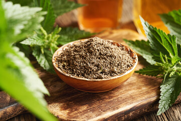 Dried stinging nettle seeds in a bowl with fresh leaves