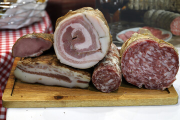 bodegón de embutidos de cerdo típicos italianos, salchichón, panceta, sobre una tabla de madera de cocina