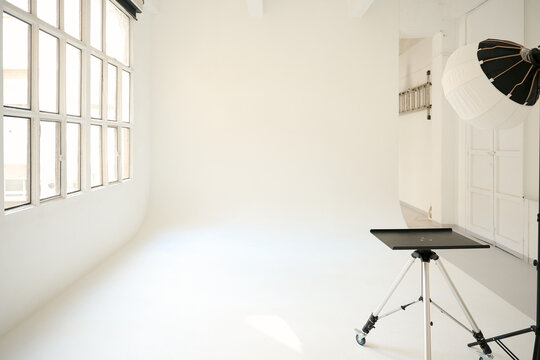 Empty photo studio with lighting equipment and large window