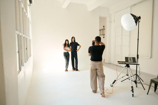 Photographer taking pictures of two fashion models in professional studio
