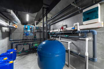 In a modern water treatment facility, various pipes and tanks are meticulously arranged. The setup includes blue tanks and advanced machinery, optimized for purification and distribution