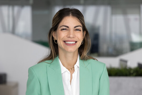 Head shot close up portrait of happy businesswoman, boss or manager dressed in elegant jacket posing with smile in workplace, feel satisfied with career growth, success and professional achievements