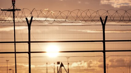 Airport fence with barbed wire during landing at sunset