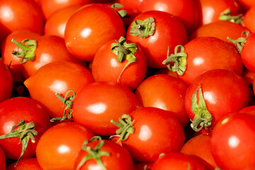 Fresh red tomatoes stacked in abundance at a local market, showcasing vibrant colors and natural textures during a sunny day