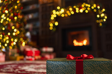 Green gift box in classical Christmas decorated interior living room library with fireplace. Christmas gift near fir tree on Christmas eve. Modern classic style interior design apartment. Christmas
