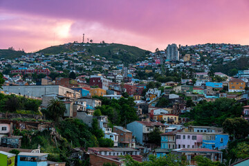 Scenic view of the sprawling, colorful hillside neighborhoods of Valparaiso, Chile, illuminated by the soft pastel colors of a twilight sky.