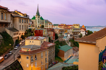 Scenic view of the sprawling, colorful hillside neighborhoods of Valparaiso, Chile, illuminated by the soft pastel colors of a twilight sky.