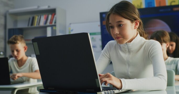 Primary School Girl Working on Creative Project on Laptop, Practicing Digital Skills in Art Class. Young Kids Drawing, Doing Tasks on Digital Devices in Modern Classroom. Interactive STEM Learning.