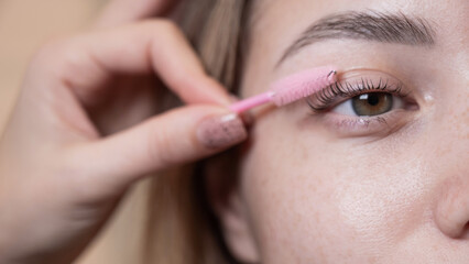 Caucasian woman brushing her eyelashes after lamination. 