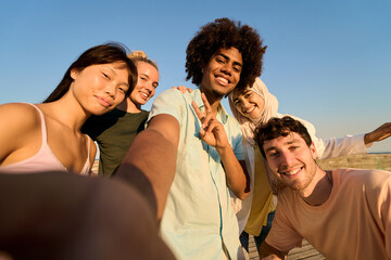 Happy multi ethnic friends taking selfie on the beach at sunset