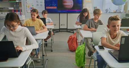 Primary School Students Working on Creative Projects on Laptops, Practicing Digital Skills in Art Class. Digital Screen Showing AI Software for Creating Pictures. Interactive STEM Learning. Dolly Shot