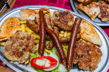 Mouth-watering close-up of a large platter filled with a variety of grilled meats, sausages, and golden French fries, perfect for a feast.