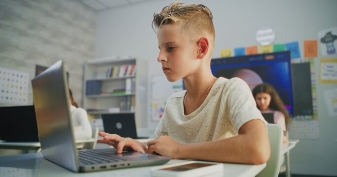 Primary School Boy Working on Creative Project on Laptop, Practicing Digital Skills in Art Class. Young Kids Drawing, Doing Tasks on Digital Devices in Modern Classroom. Interactive STEM Learning.