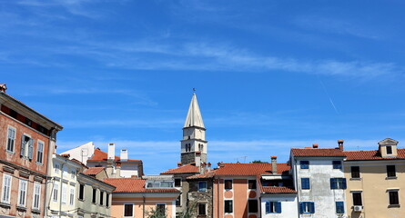Naklejka premium Kirchturm von Izola hinter bunten Hausfaasden