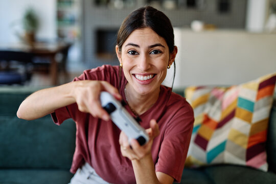 Portret of a young latina woman having fun playing video game on console computer with joystick  at home - Powered by Adobe