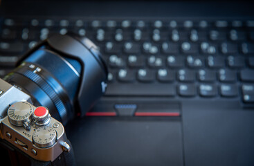 Modern digital mirrorless camera resting on laptop keyboard