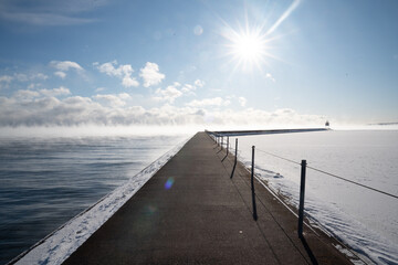 Obraz premium Snow-covered pier leading to lighthouse on frozen Lake Superior