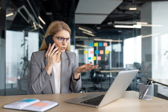 Frustrated businesswoman on phone call while at desk in modern office