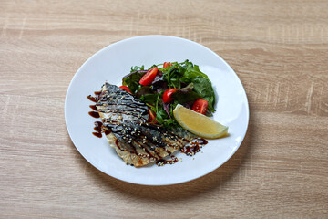 Grilled mackerel with salad and lemon wedge