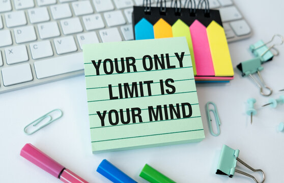 Naklejki A green and white sign that says Your only limit is your Mind is on a desk wit