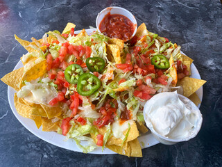 A delicious and colorful appetizer of nachos Grande with salsa and sour cream looks inviting