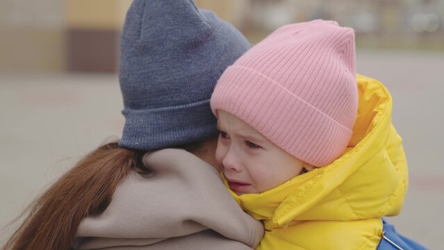 little child crying on shoulder mother, mother hugs capricious kid girl, daughter bad mood, baby shows her displeasure parent with hysteria, close-up, child expression of emotion with tears, sad face.