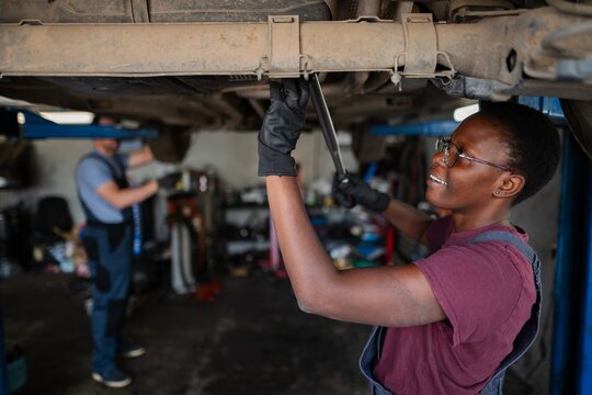 Young african female mechanic repairing car in auto repair shop