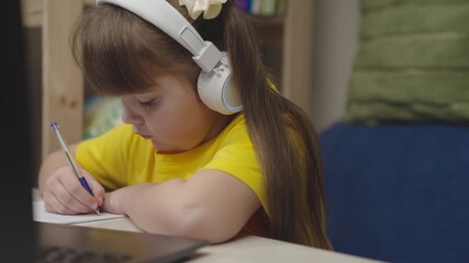 little schoolboy student writes mathematics notebook. child kid solves difficult learning problems. child education program. girl headphones with digital laptop writes notebook. study work home desk - Powered by Adobe