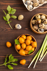 Pile of smoked quail eggs in bowl on a brown wooden background. top view