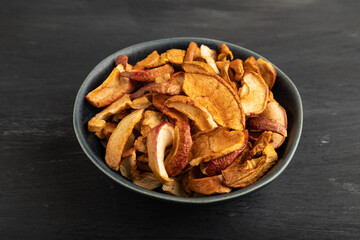 Dried Apples in ceramic bowl on black wooden. Side view, close up