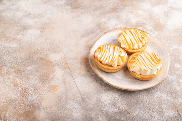 French lemon tart with meringue on brown concrete, side view, copy space