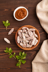 Small smoked Chicken sausages in wooden bowl on brown wooden. top view, flat lay, close up