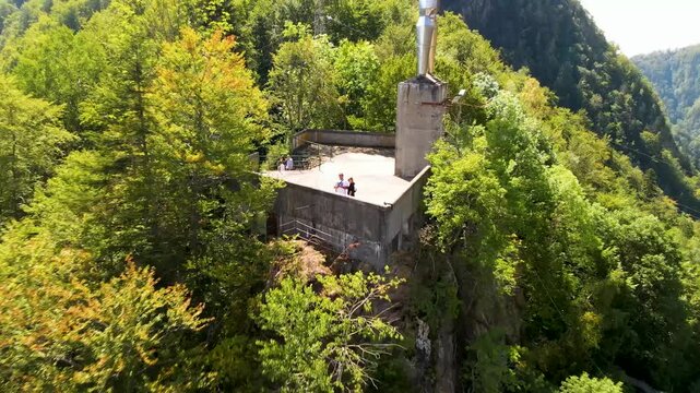ourists film themselves with a drone near Barajul Vidraru Dam on Transfagarasan Highway, Romania.