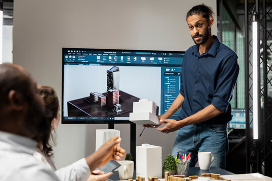 Male real estate engineer presenting smart city design and buildings layout, creating a master plan with his team for modern residential infrastructure growth and property investment.