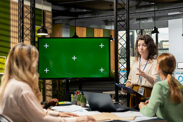 Corporate women gathering next to chroma key screen in modern office work environment, evaluating financial data, strategic indicators and other information during boardroom meeting.