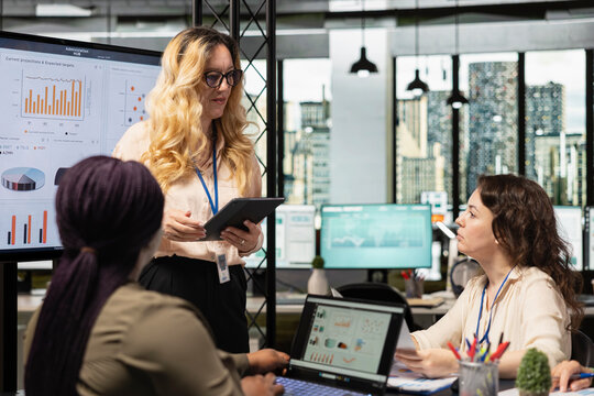Ambitious group of multiethnic women collaborating in a modern office, discussing progress indicators, sharing insights and setting the foundation for a corporate success story.