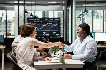 HR professional shaking hands with female candidate after being accepted within the organization, filling in the new job position after a successful interview. People reaching agreement for hiring.