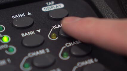 Man deactivates Blackout on lighting console - button stops blinking, close-up in 4K