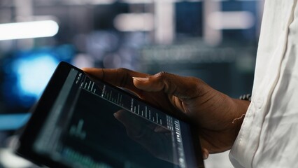 Close up of data center software developer using tablet to review code for automation scripts. Server hub IT specialist using device, monitoring error logs for debugging processes, camera A