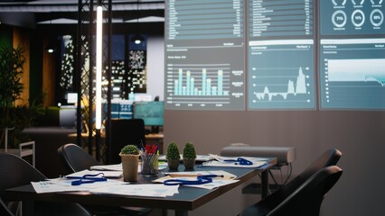 Professional workspace in a multinational enterprise shows an empty dark office after hours, glowing with data insights, forecasting projections and digital charts for business planning.