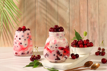 Fruit yogurt with cherries and fresh cow cream for healthy nutrition in a glass on an elegant table. Healthy breakfast with ingredients, kitchen background. Natural food and detox diet concept