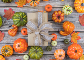 Top view natural gift box with burlap ribbon and mini pumpkins on wooden table