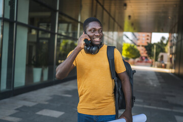 Architect walking and talking on phone holding blueprints